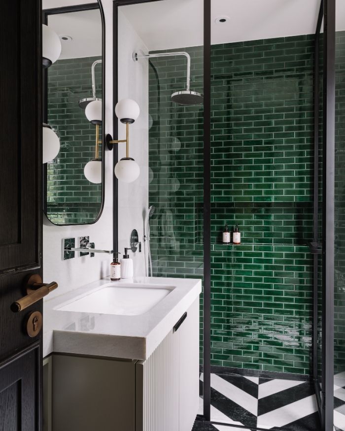 Bold in deep green tiles with chevron stone and a steel-framed shower, the bathroom is a lesson in contrast, where clean design meets deep hues; Photography by Ishita Sitwala