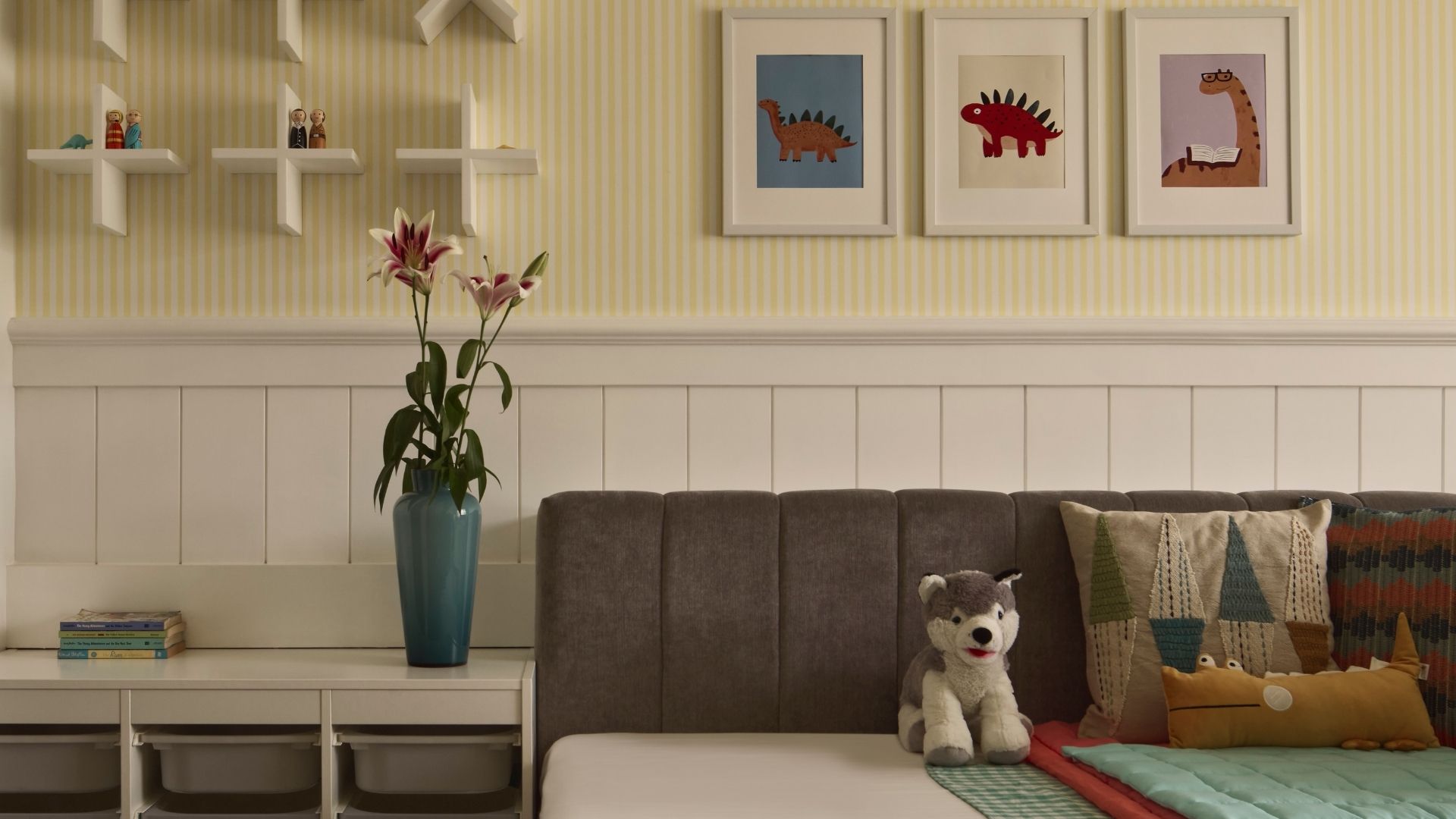 The kid’s bedroom feels like a sunny story unfolding in shades of yellow and white. The engineered wood floor warms every step, while striped yellow wallpaper from Gita Enterprises brings a playful rhythm to the walls. Pops of artwork from Etsy add charm and character, and soft furnishings from Bharat Furnishings make the space cosy and inviting. Cushions from Sarita Handa add bursts of texture and comfort; Photography by Yadnyesh Joshi