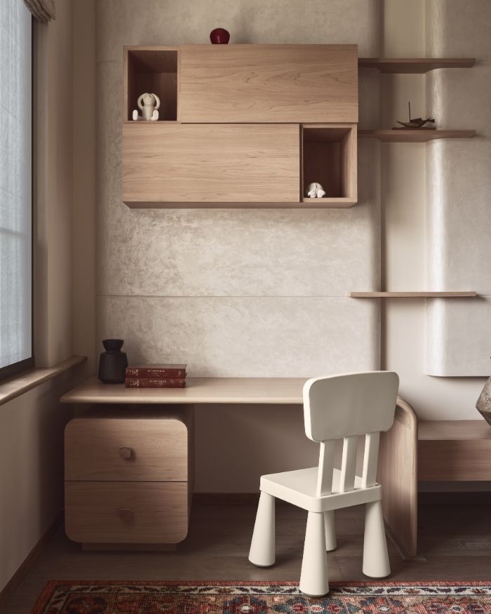 The study table is paired with a beautifully crafted wooden chair. Behind it, the stone-finish wall adds character, while a framed artwork on the soft beige wall brings a quiet touch of personality; Photography by Yadnyesh Joshi