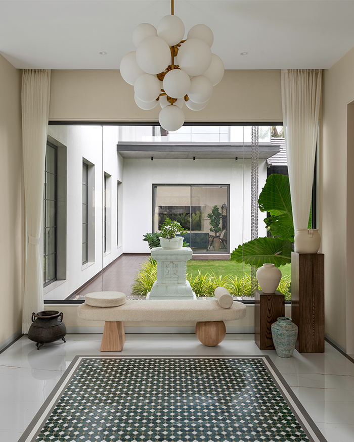 Foyer with black and white grounding and a cream hued seat overlooking the garden