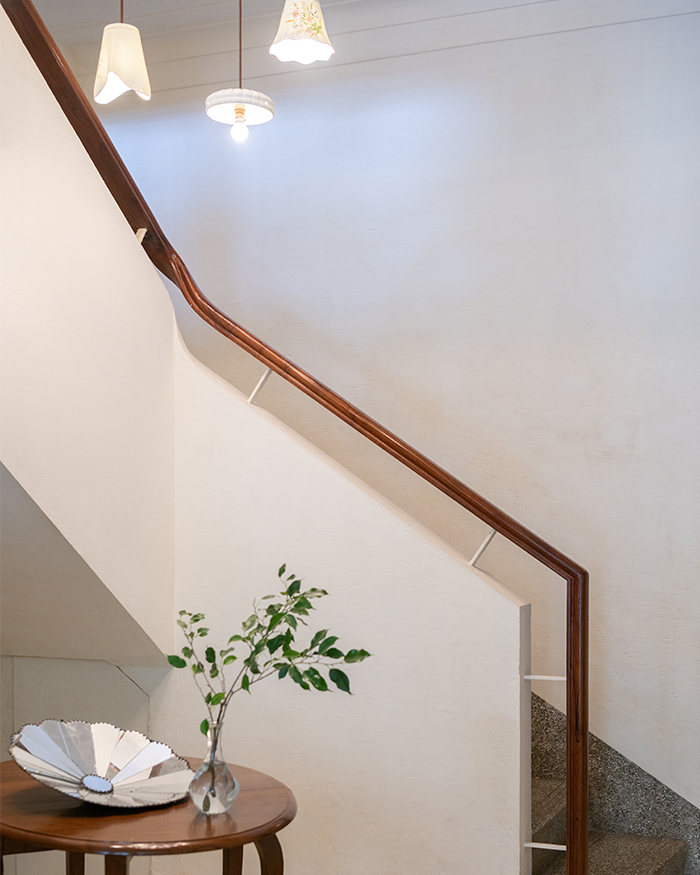A curved stairway highlighted by charming chandelier lighting; Photography by Hashim Badani