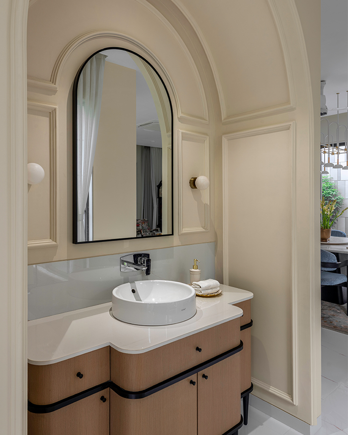 An arch looming over the sink with a framed mirror above