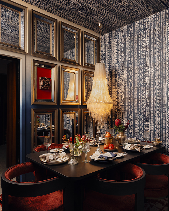 Blue African prints sweep across the walls and ceilings of the dining room with golden mirrors on the wall; Photography by The Matter Studio