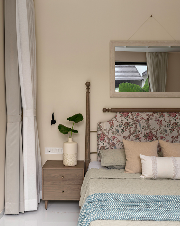 A wooden nightstand and muted pastel bedsheets adorning the bed