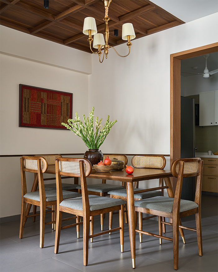 A custom-made Furniselan dining table set beneath a wooden ceiling crafted by the studio’s in-house carpentry team. The wall art, created using a repurposed traditional rug; Styling by Amol Nalavade; Photography by Manthan Yadav