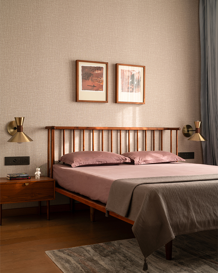 Crafted from reclaimed golden teak by Vernacular Modern, the lightweight frame is set against a richly textured mud-plastered wall; Photography by Nayan Soni