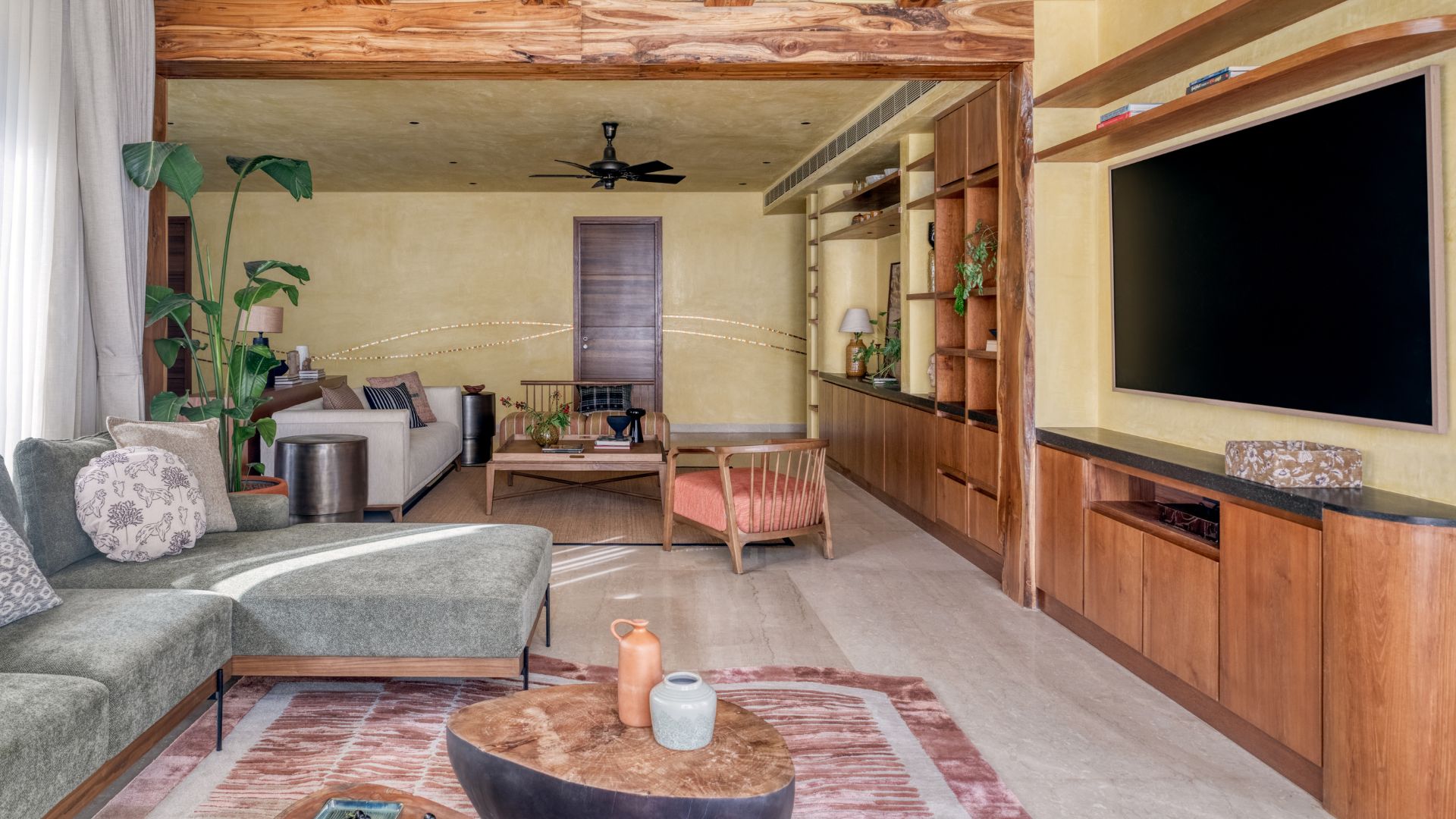 Spacious living room featuring wooden TV unit, lime washed walls, neutral sofa and earthy decor accents.