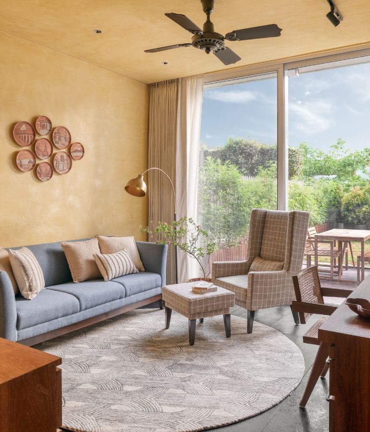 study area with sofa, armchairs, large windows, indoor plants and neutral textured walls