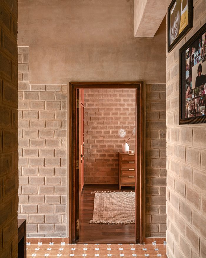 Bedrooms unfold behind teak doors, echoing the home’s grounding earthy palette; Photography by Nayan Soni