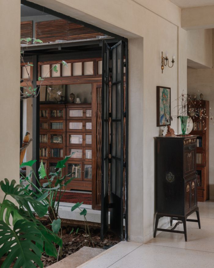 A folding door opens to a courtyard as wooden cabinets and artefacts shape a quiet passage between inside and out; Styled by Imran Ali Khan and Rishad Patel; Photography by Shantanu Starick