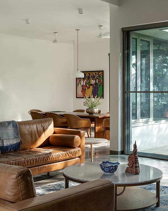 An antique brass
prabhavali from Souk frames
a red Burmese lacquerware
offering vessel flanked by
oriental Southern Official hat
chairs sourced by the residents
during their time in South East
Asia. In the foreground sits a
Jaipur Rugs carpet; Photography by Shamanth Patil J