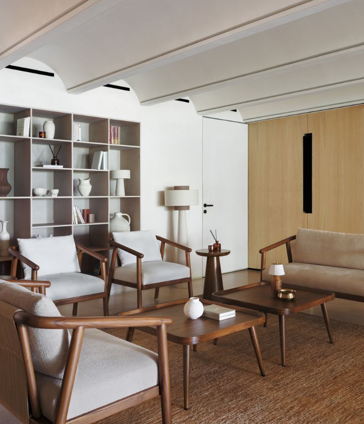 The lounge blends wooden furniture with beige toned upholstery and open shelving; Photography by Suleiman Merchant