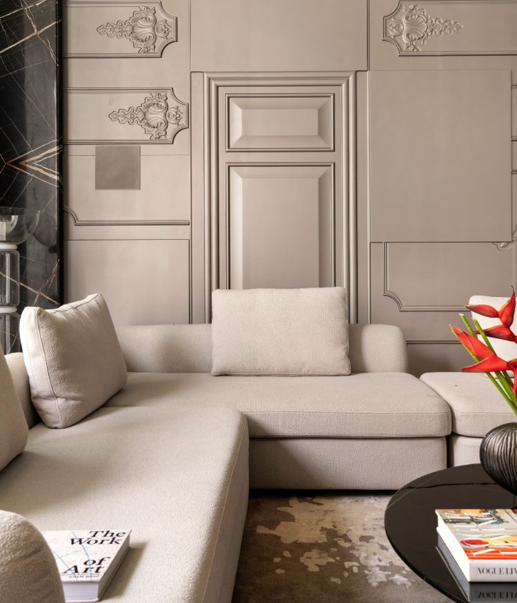A close read of the drawing room's hand-cast plaster relief — classical cartouche motifs finished by Viero , alongside a Nero Marquina marble column. Cream modular sofa and carpet by Dhiri Rugs in the foreground; Photography by Avesh Gaur; Styling by Shivani Raina