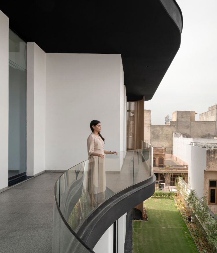 From the curved upper balcony - glass balustrade by Technal India , the first-floor raised lawn comes into view. Photography by Avesh Gaur; Styling by Shivani Raina