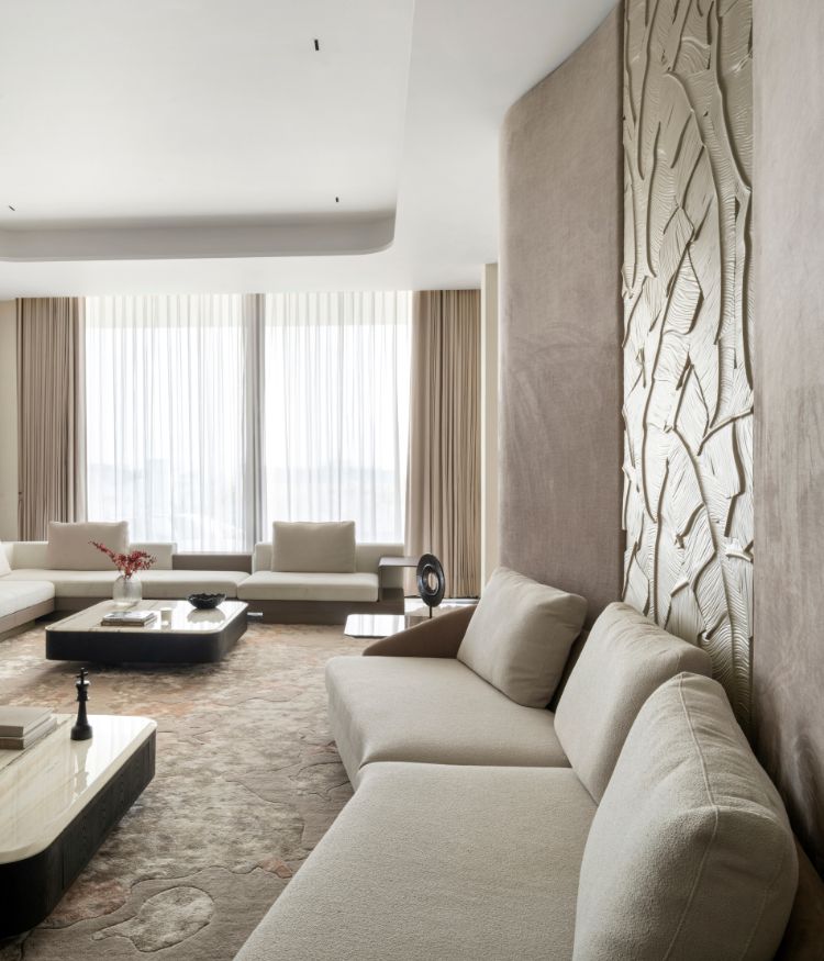 The family lounge's accent wall: a full-height microcement bas-relief of sculpted branches and leaves by Viero and Roschcrete. Cream sectional sofa and carpet by Dhiri Rugs in the foreground; Photography by Avesh Gaur; Styling by Shivani Raina