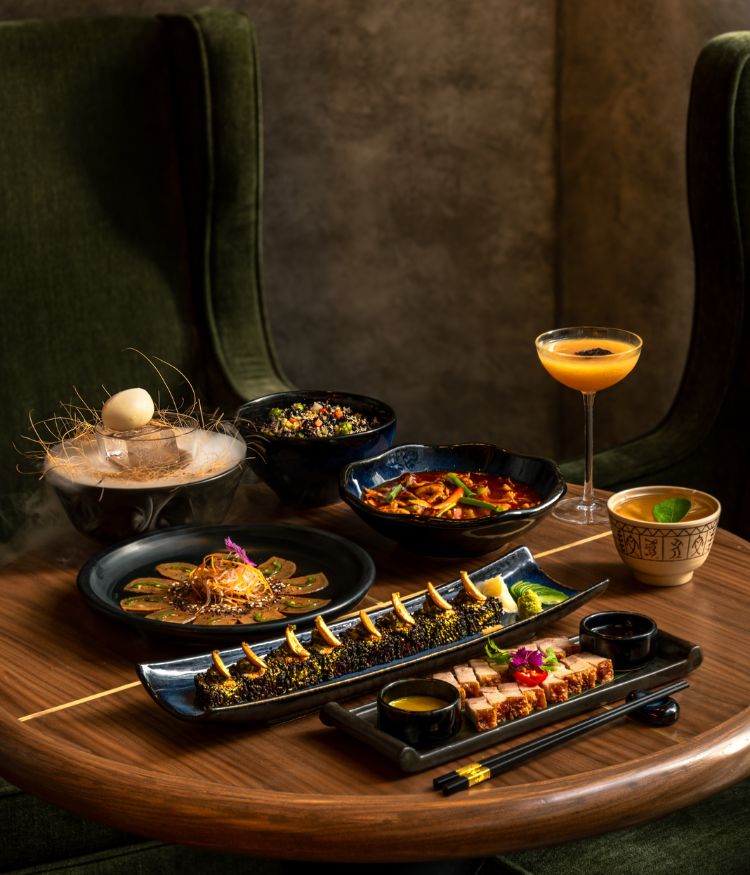 Table spread of modern Asian cuisine featuring sushi, dumplings, small plates and cocktails in a restaurant