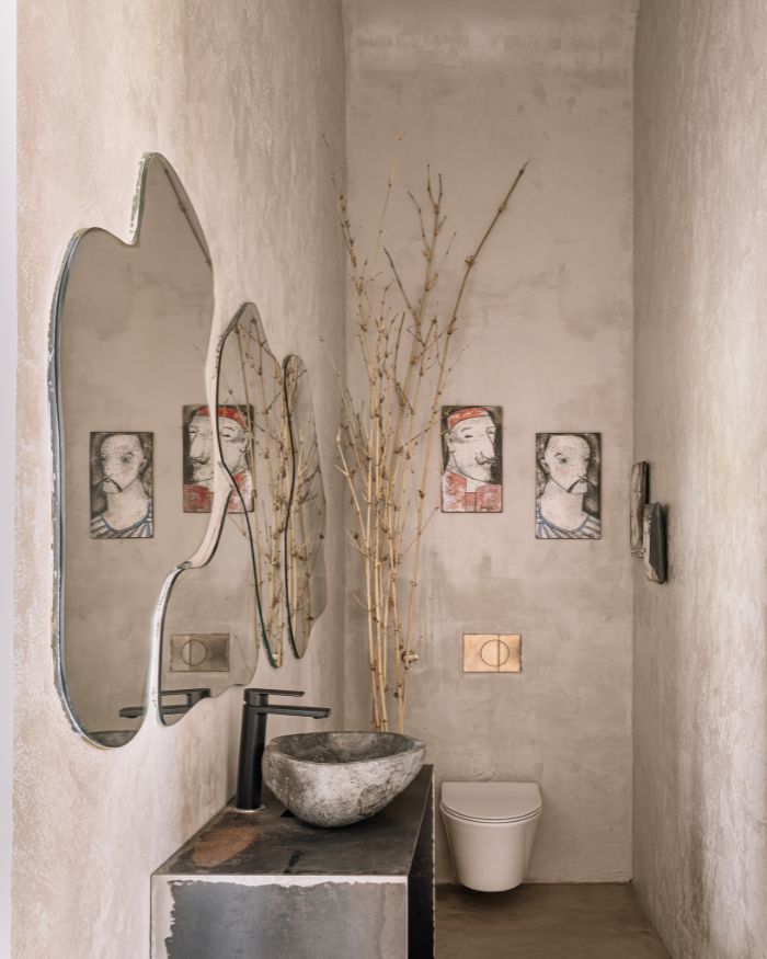 Housing a rustic iron vanity and a collage of mirrors, the powder room embodies a rustic appeal; Photography by Ishita Sitwala