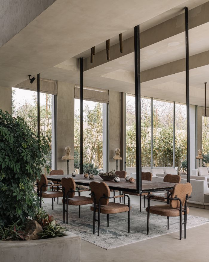 A glimpse into the dining room where the dark-hued chairs complement the tonality of the space. The plants reflect and continue the greenery of the bamboo garden outside; Photography by Ishita Sitwala