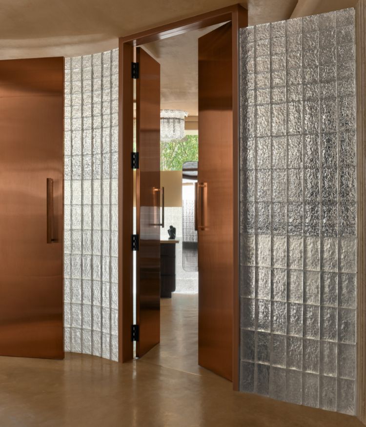 Brown-toned wooden doors framed by textured glass bricks; Photography by Gokull Kadam