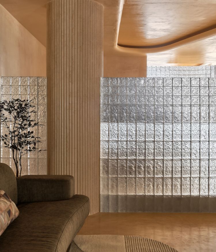 The waiting area features muted beige colour palette and diffused light from the glass bricks; Photography by Gokull Kadam
