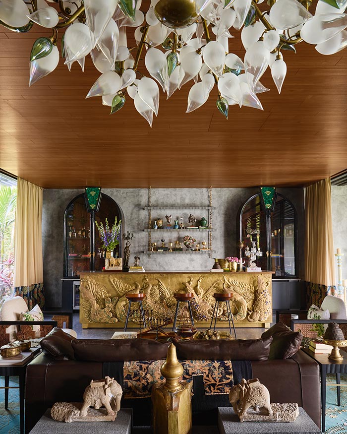 In the cocktail room, a brass repoussé bar by Vikram Goyal takes centre stage. Atop it, pieces sourced from Jain Handicrafts, Beg Borrow Steal Home, and The Charcoal Project add layered detail, while a chandelier from Klove Studio crowns the space. Assorted accessories from Kochi sit alongside elephantine architectural elements by Mahendra Doshi; Photograph by Talib Chitalwala