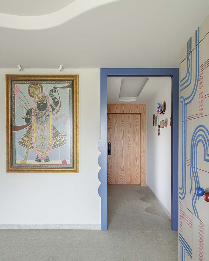 The artwork anchors the corridor against a contoured blue threshold that frames the transition between spaces. Flooring is Marca Corona from KlayStore; Photography by Wabi-Sabi Studio
