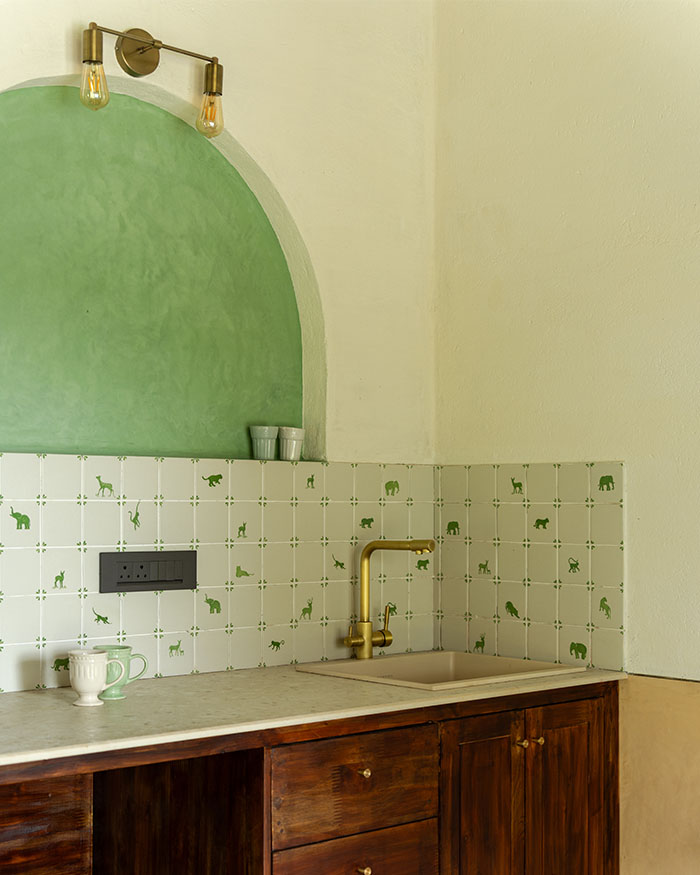 A green arched niche frames the guest room pantry. Wall lights by Nauticaz and oxide and lime plaster finish by Earthly Yours; Photography by Syam Sreesylam