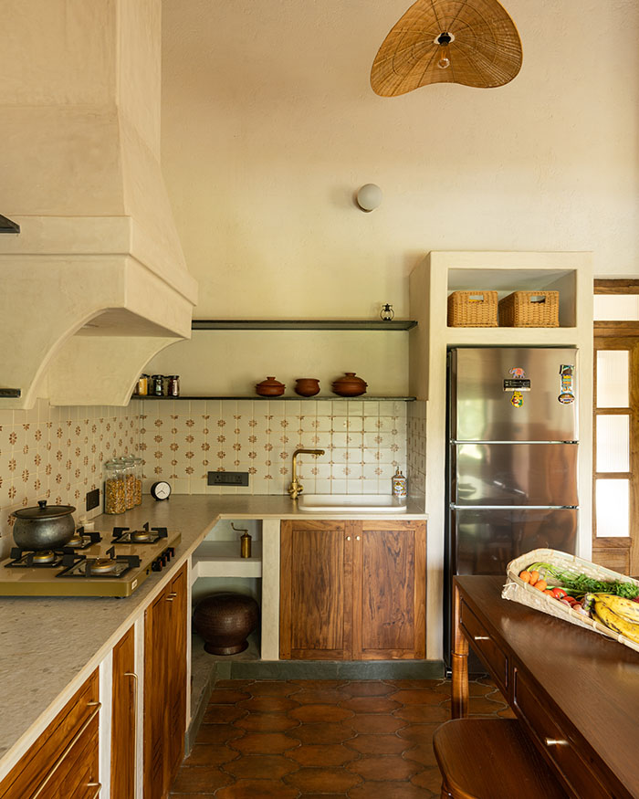The compact kitchen balances utility with character. Terracotta flooring is by Paradise Stile Studio, pendant lights are by Akway and banana fibre blinds are by Ind Eclectik; Photography by Syam Sreesylam