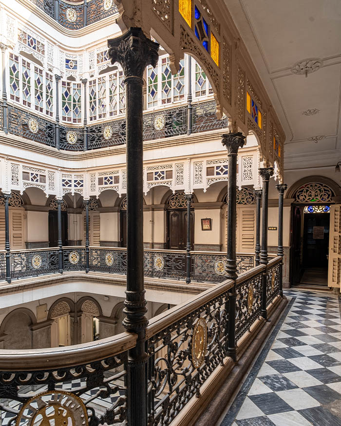 Ornate cast iron fretwork forms the continuous railings along the home’s deep passages, which gaze into the central courtyard; Photography by Rohit Ganguly