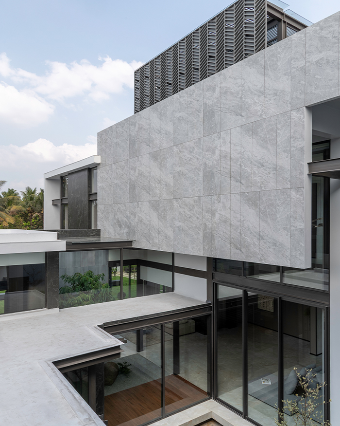 Stone-clad volumes and glazed openings shape the home’s contemporary facade; Photography by Sebastian Zachariah, PHX India