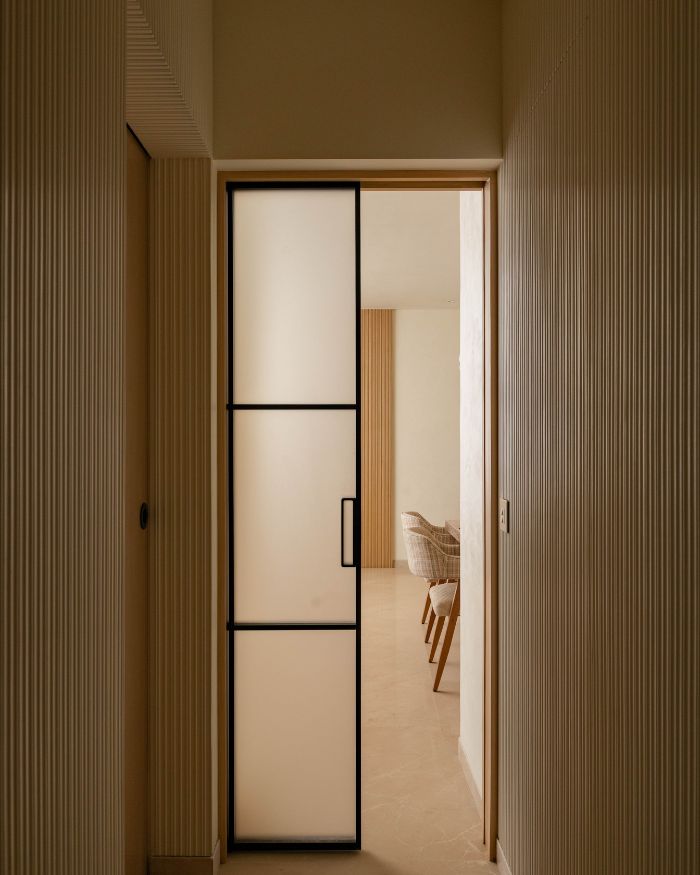 A translucent sliding door separates the communal living space from the privacy of the bedroom, marked by textyred walls on both sides; Styling by Riddhika Jesrani; Photography by @thekuber @evolve.studio_