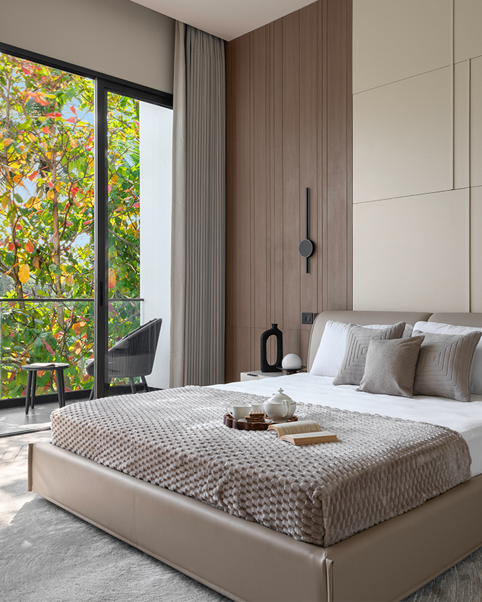 Wooden flooring and brown tones shape the light-filled bedroom. Headwall by Lixil and windows by Technal; Photography by Sebastian Zachariah, PHX India