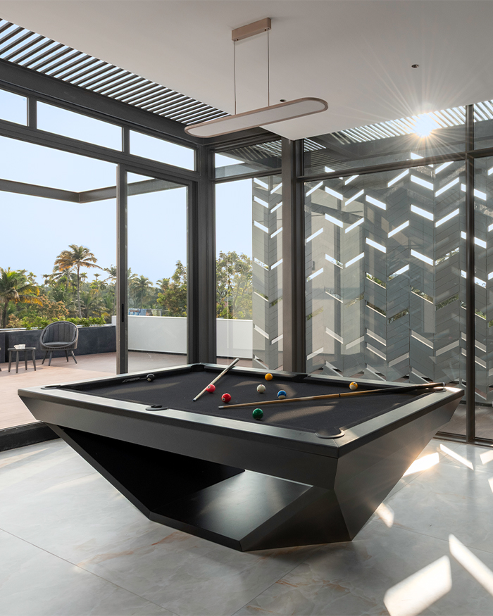Patterned screens filter sunlight into the entertainment room, creating shifting shadows across the pool table; Photography by Sebastian Zachariah, PHX India