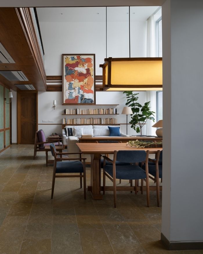 A custom dining table sits beneath a pendant light alongside a colourful artwork; Photography by Hemant Patil