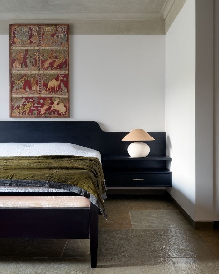 Balancing simplicity with artisanal detail, the bedroom layers earthy textures alongside an artwork by Memeraki, soft furnishings by Suta, rug by Jaipur Rugs, lamp by Gulmohar Lane and lime finish by The Concrete Works; Photography by Hemant Patil