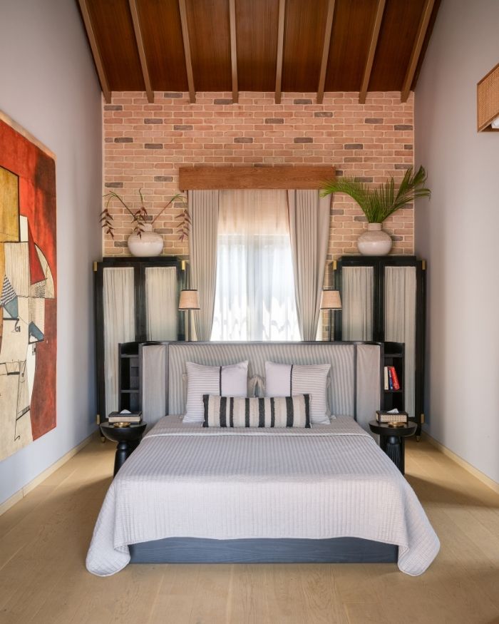 The exposed brick wall weaves together furniture by Meher Sra Designs, accessories from Rangeela Goa, a bed by Altrove and a Mirror from Pottery Barn; Photography by Nayan Soni