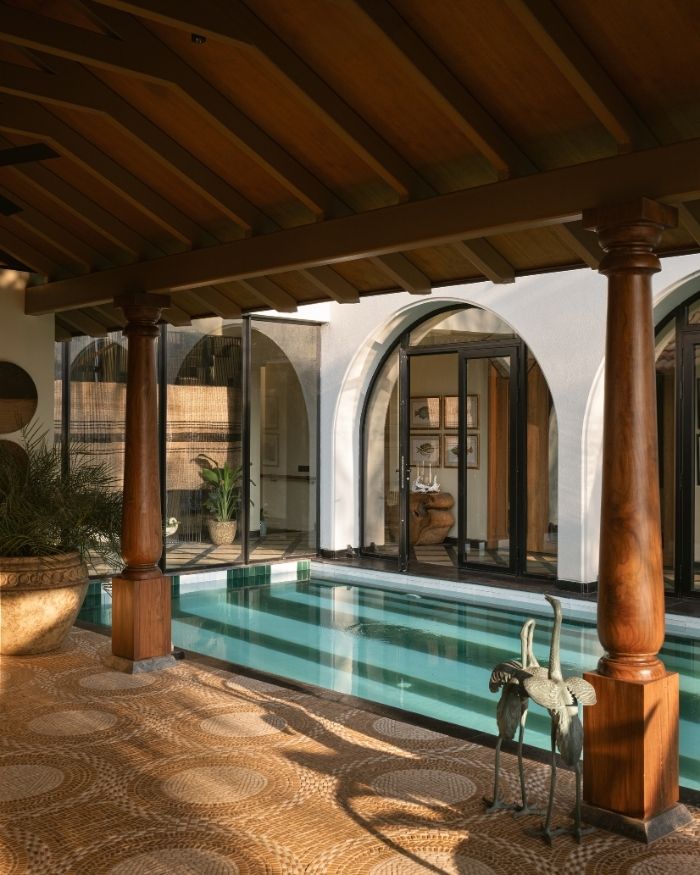 Ivory and mustard pebble mosaic borders a green-and-white striped pool floor by Keramos; Photography by Nayan Soni