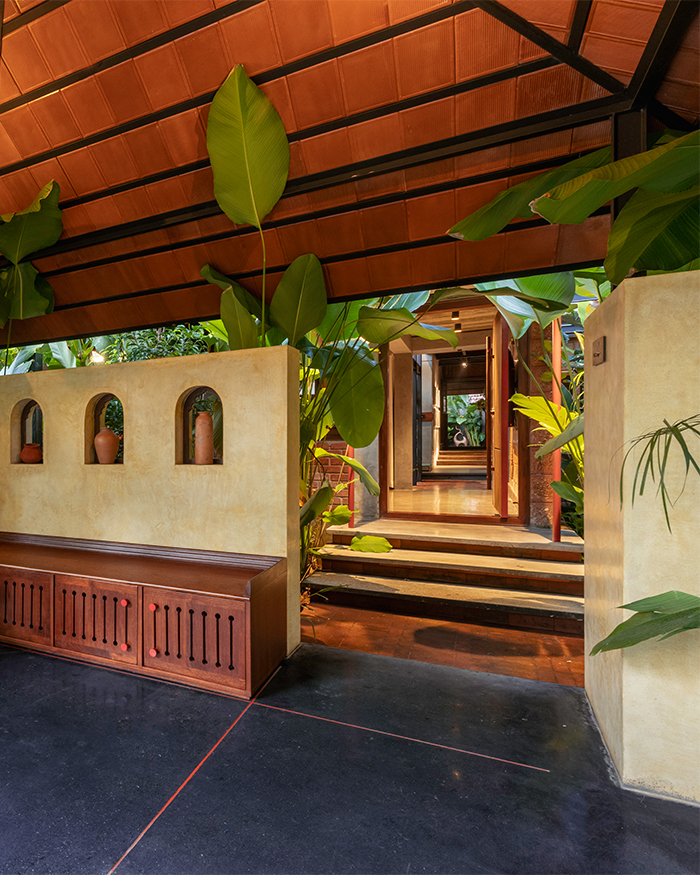 Arched niches, warm timber detailing and oversized tropical foliage create a seamless transition between architecture and nature; Photography by Ar. Prashanth Mohan of Running Studios