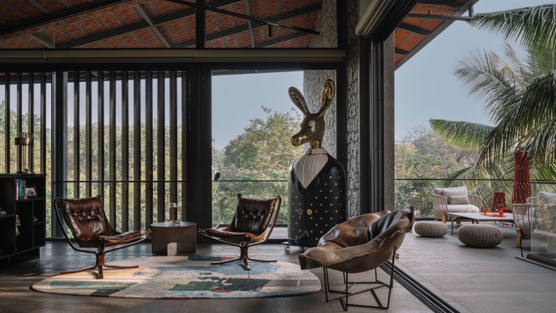 The sloping roof atop the generously ventilated bar and coffee area is a key feature in the remarkable facade of the house. A tad more marvellous is the curious metallic donkey, the Ciuco cabinet from Scarlet Splendour, designed by Matteo Cibic. A vibrant rug from Cocoon Fine Rugs sets the base for a lone Poltrona Frau chair (right) and two other chairs sourced from flea markets in Paris. All outdoor furniture in the sit-out area comprises sturdy seating designs from Talenti; Photography by Ishita Sitwala