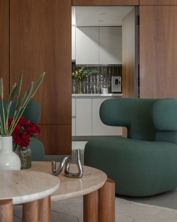 A pop of colour amidst the wooden paneling adds a touch of earthiness to the living area. The arrangement also works as a smart concealment of the kitchen door, without obstructing visual flow. The coffee table is from West Elm; Photography by Kuber Shah