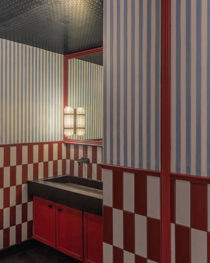 The washroom features a bold and playful design
language, combining blue-and-white striped wall
treatments with red-and-white checkered tilework; Styling by The Orange Lane; Photography by Kuber Shah