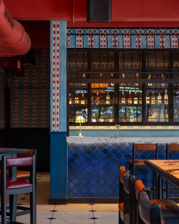 A stylish bar featuring rich blue tiled finishes, elegant
marble top, and custom black metal and glass shelving
that elegantly showcases the liquor collection; Styling by The Orange Lane; Photography by Kuber Shah