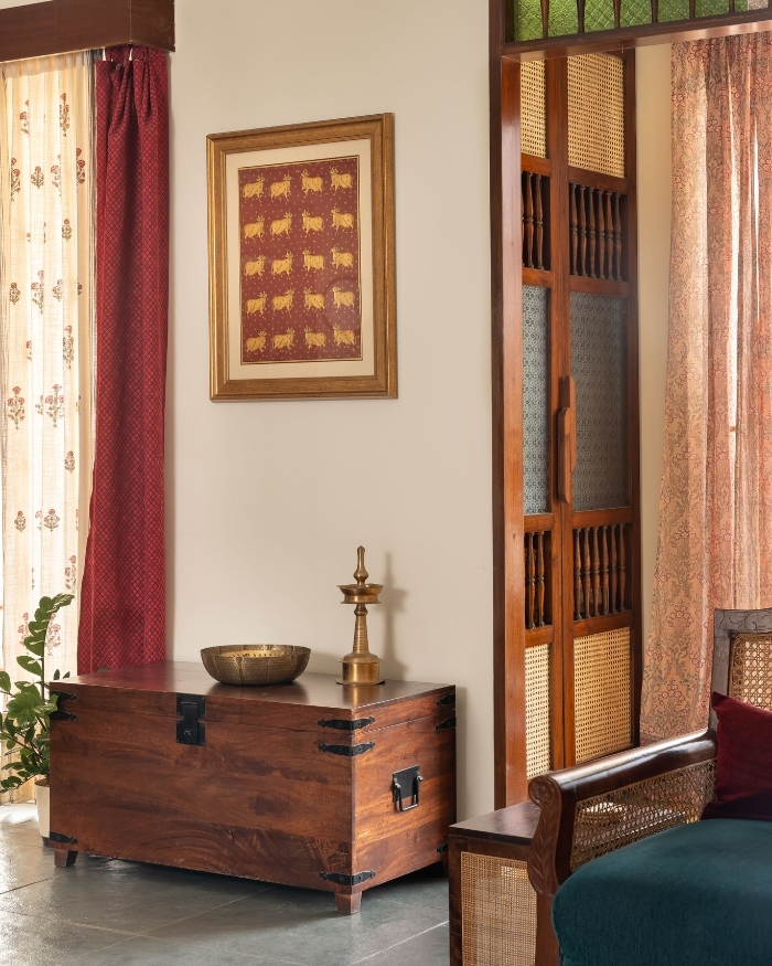 A vibrant Pichwai painting marks the transition between the living room and pooja nook, alongside curtains from Fabindia; Photography by Shine Parsana