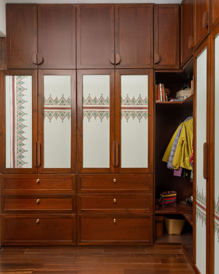 In keeping with the dwellingβs heritage-inspired language, the master walk-in closet comprises wood cabinetry accented with traditional printed textile from Aruvi Homes; Photography by Shine Parsana