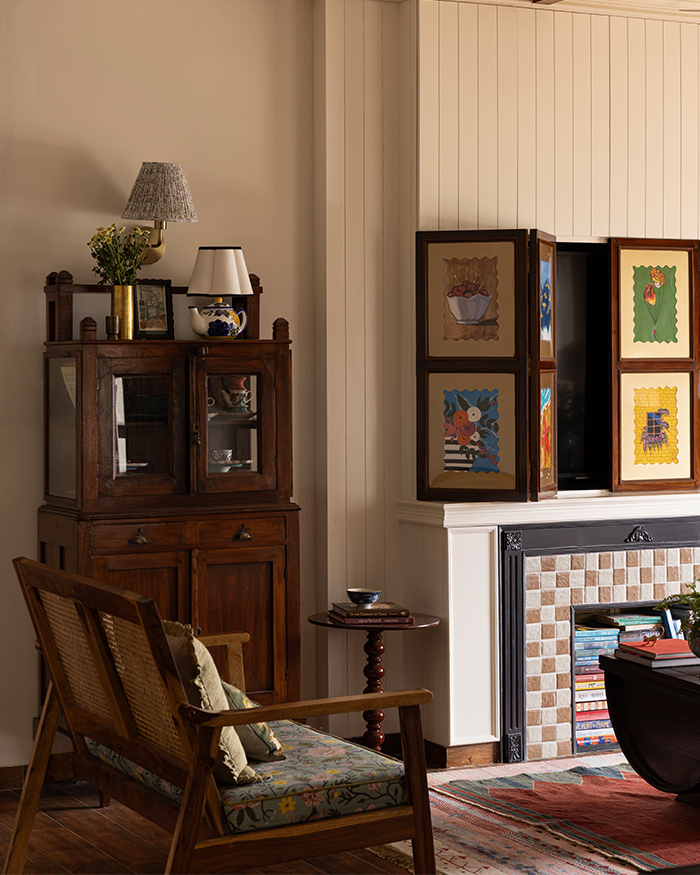 Concealing electrical
wiring within, the fireplace doubles as a storage lined with books, while on top,
the television disappears behind shutters composed
of paintings. A warm red weave from Jaipur Rugs; Styling by Shivani Raina; Photography by Phosart Studio
anchors the room