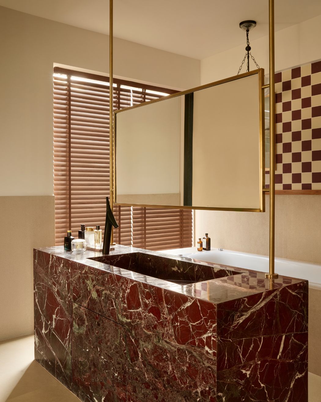 A monolithic vanity carved with Red Rosso Levanto marble takes center stage in the bathroom with an integrated sink basin. Kohler & Nexion Tiles Styled by Namrataa Shetty; Photography by Talib Chitalwala