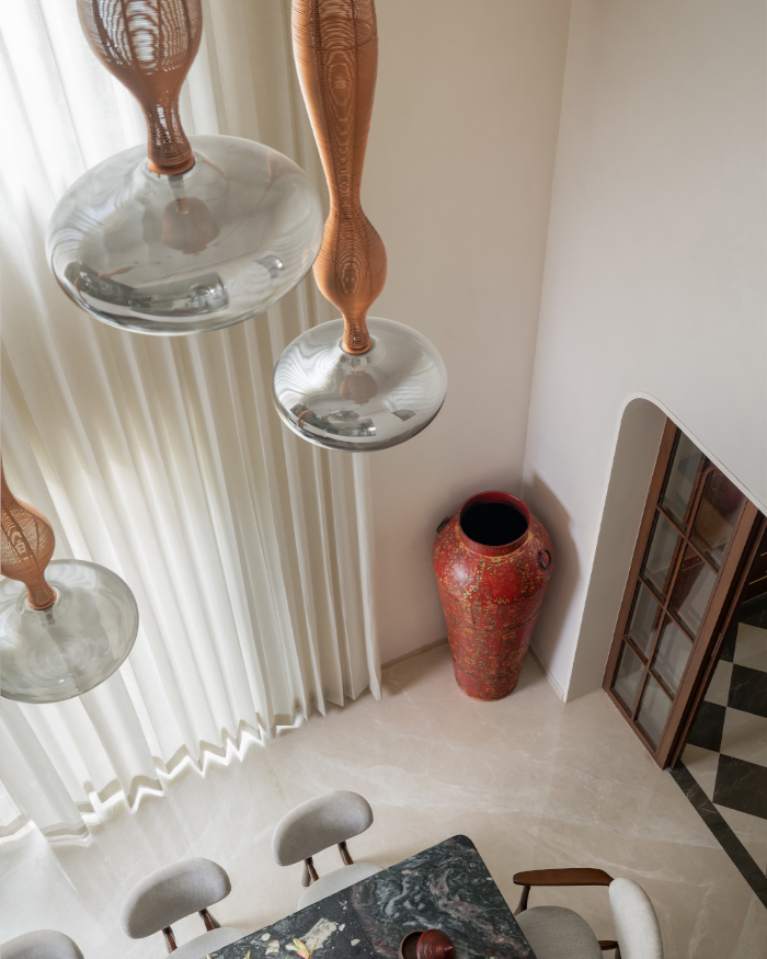With dusk lights by Yaahvi hanging above the dining, completed with a tramo chair from Magari and a red vase from Curious Hues, contrast the space; Styling by Apoorva Nayak, Photography by Arjun Krishna