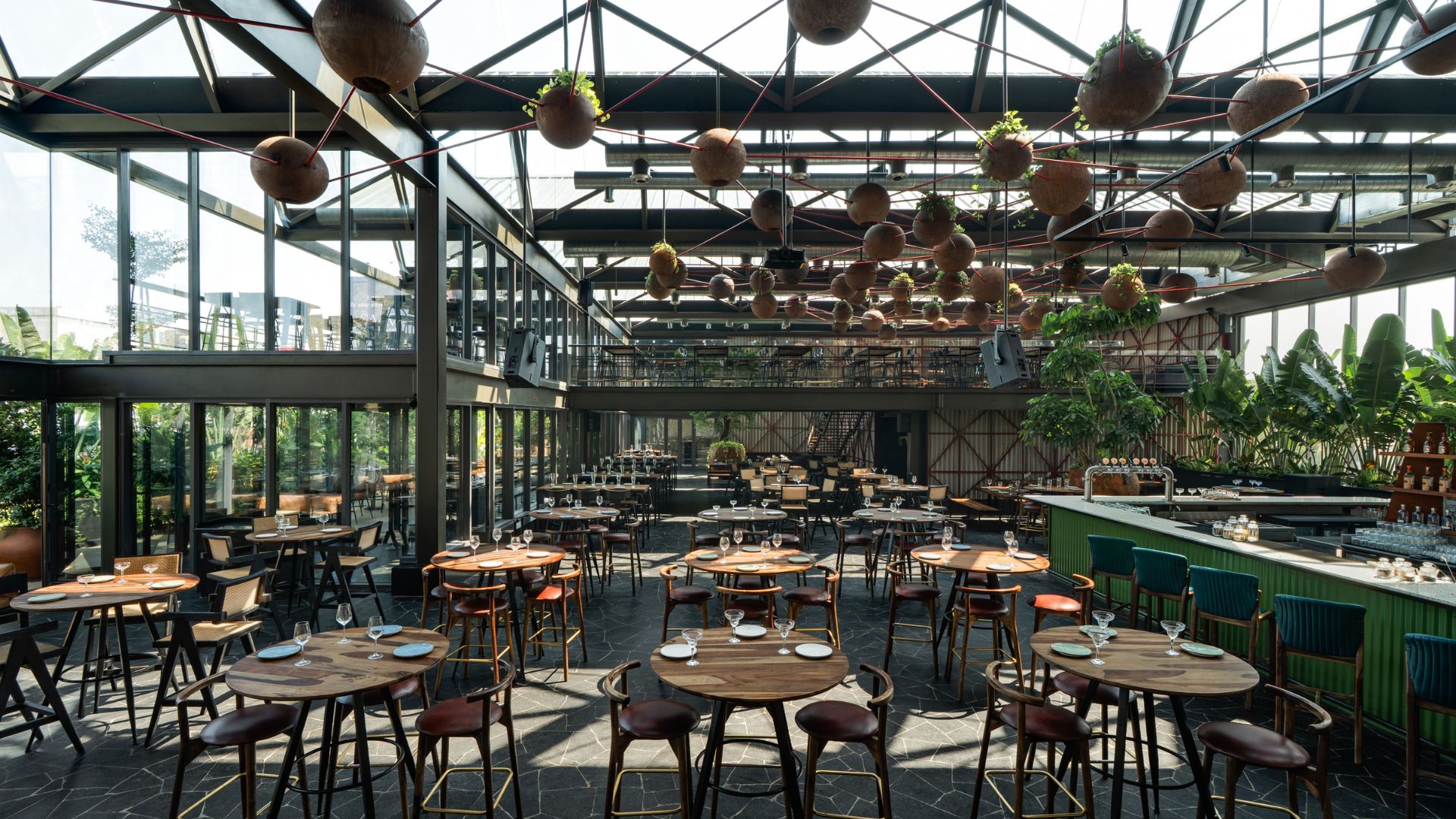 Rows of round tables in the sunlit seating area near the playfully green bar counter