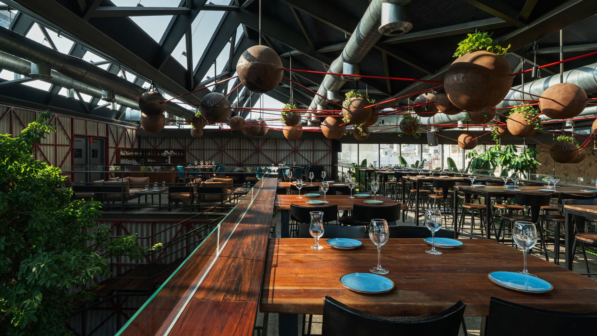 Potted foliage and petrol blue plates temper the industrial character of the VIP lounge