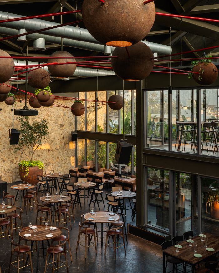 Inner dining area with round tables; spherical installations on the ceiling offer a contrast to the industrial character while dark-toned flooring adds a moody touch